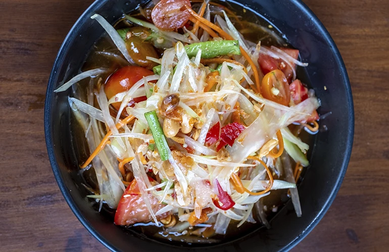 Ensalada de papaya verde (som tam) en un cuenco negro