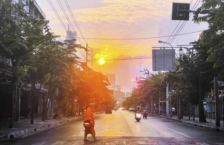 Monje cruzando una calle al amanecer en Bangkok