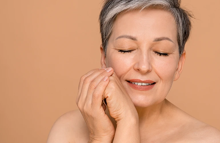Mujer madura con piel saludable tocando suavemente su rostro