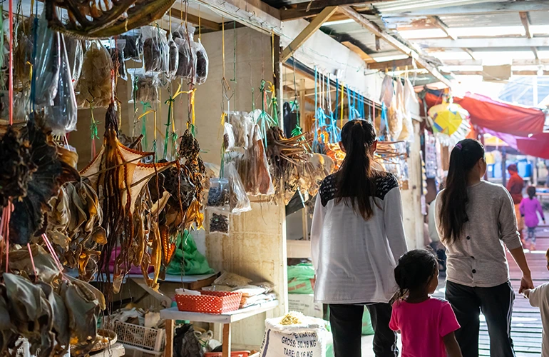 Mercado local en Tailandia con productos secos colgados y familias paseando
