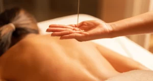 Aceite de masaje cayendo sobre la mano antes de aplicarse en la piel de la espalda