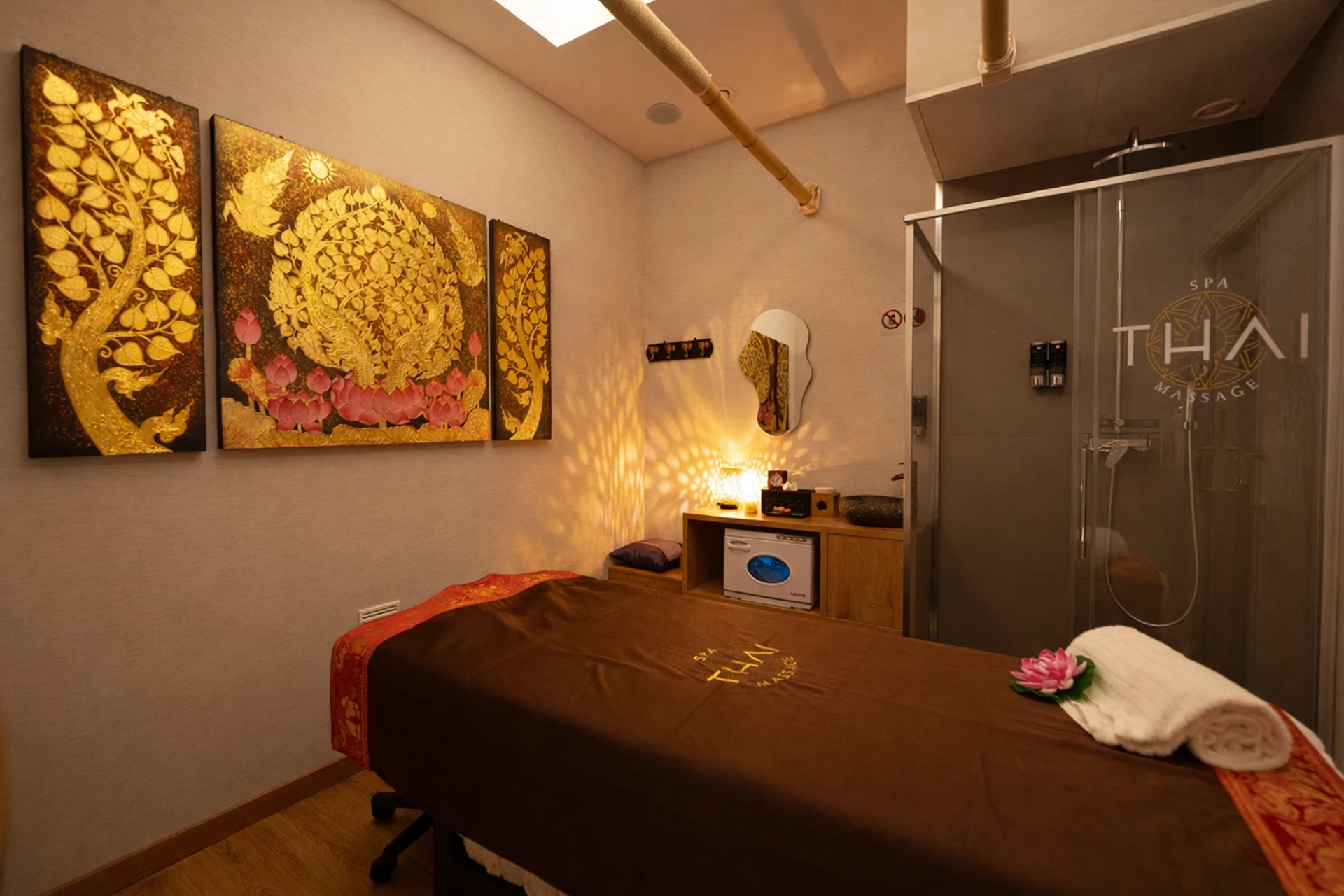 Sala íntima de tratamiento con tríptico dorado y flor de loto en centro de massatges tailandesos Barcelona