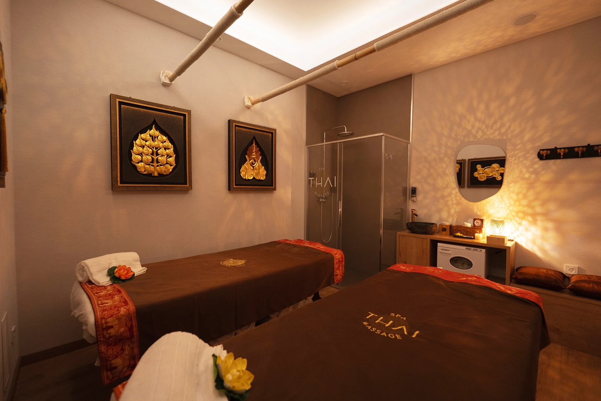 Sala con dos camillas paralelas para masaje en pareja con cuadros del árbol Bodhi en spa thai Eixample