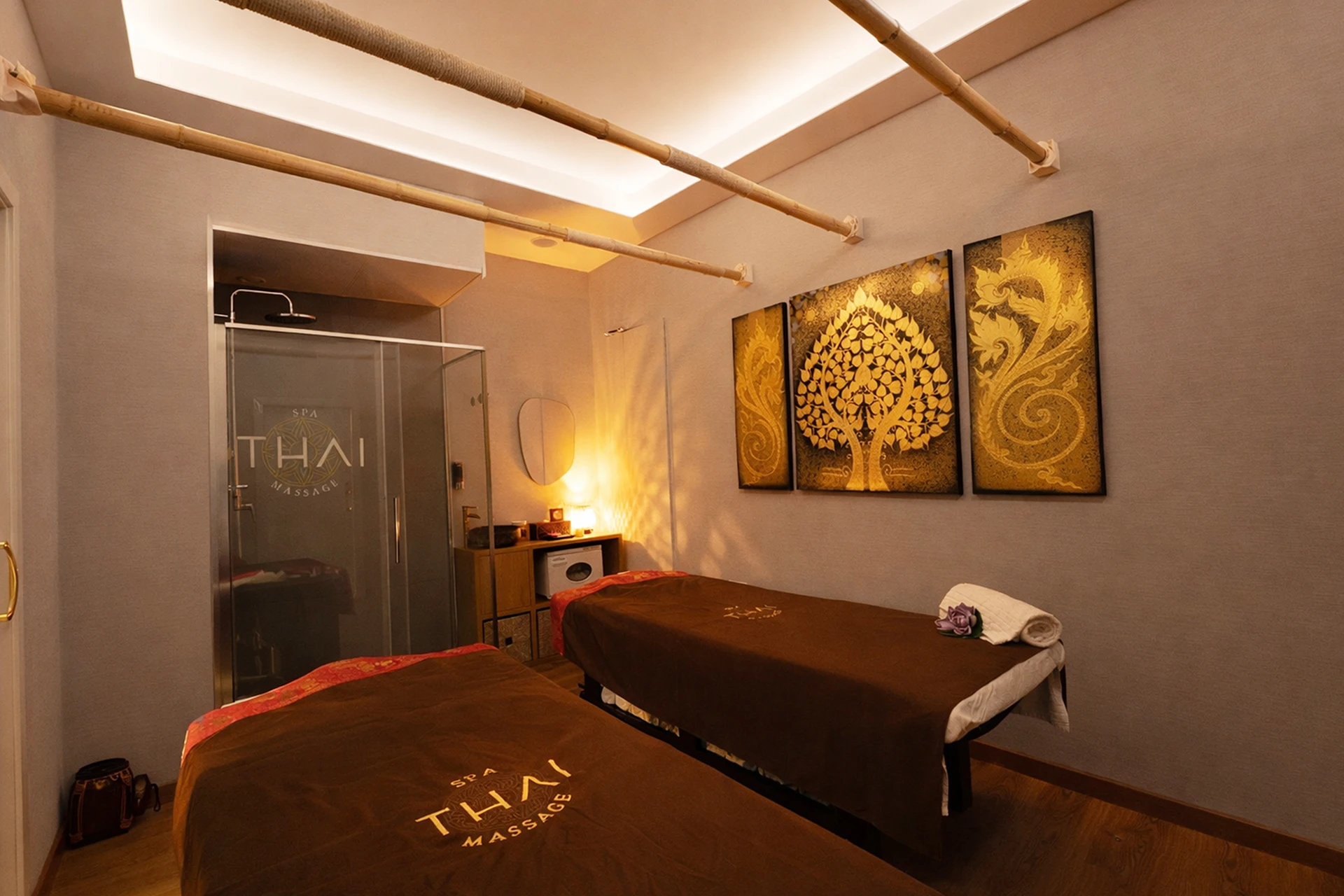 Sala con dos camillas en disposición en L y arte tradicional Lai Thai en spa cerca del Eixample