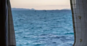 Cómo relajarse para dormir: ventana abierta al mar al anochecer junto a la cama