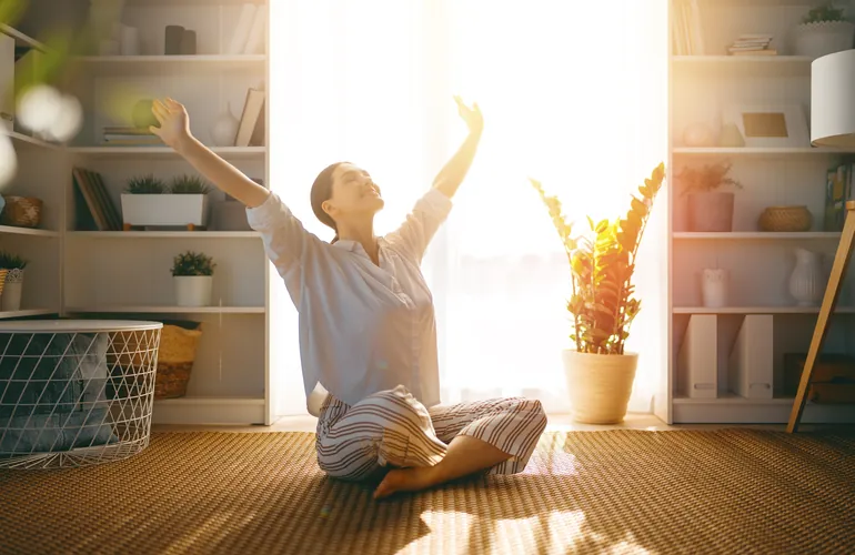 Mujer estirándose y respirando junto a la ventana para relajarse antes de dormir